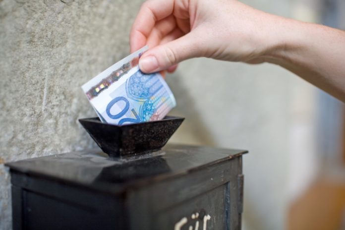 Een vrouw stopt geld in een brievenbus